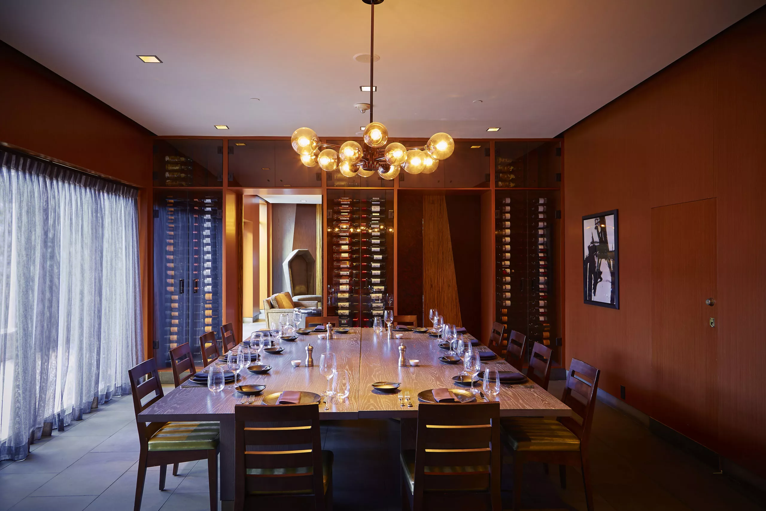 Private dining table at Knife with a large wooden table with seating around, a wine rack on the entrance wall with the table set for Brunch at Highland Dallas, TX