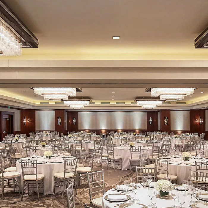 Ballroom at Highland Dallas set for a wedding with white linen tables, silver ballroom chairs and white floral arrangements in Dallas, TX