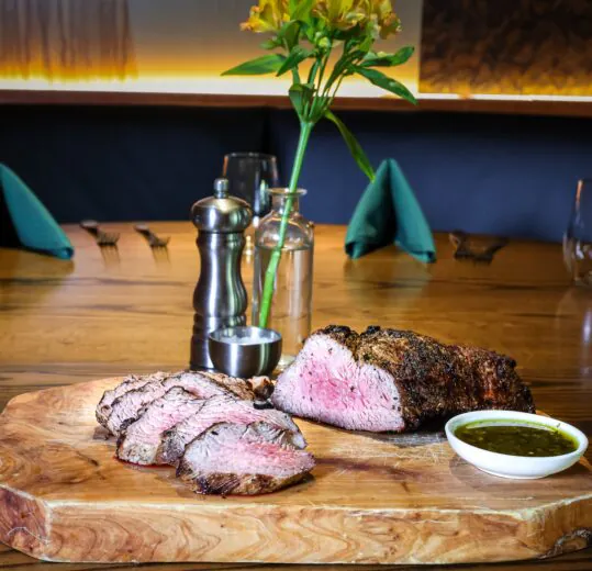 image of a juicy steak and slices on board set in the middle of a table