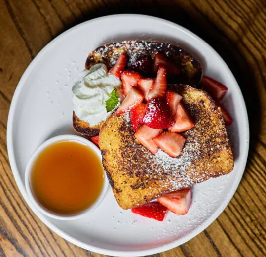 delicous french toast, syrup and whip cream on a white plate